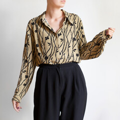 Woman wearing elegant pattern shirt and black trousers isolated on white background.