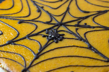 Pumpkin pie. A cake decorated on Halloween with a black cobweb of chocolate. Chocolate spider in the web