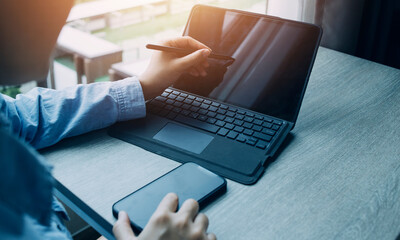 Businessman hands working with finances about cost and calculator and laptop with tablet, smartphone at office in morning light