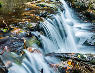 Fototapeta na wymiar Blurred waterfall throughing mossy rocks