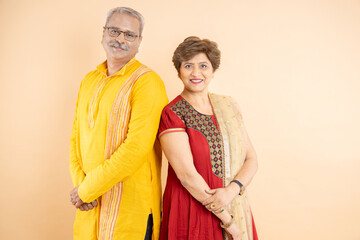 Happy senior indian couple wearing traditional cloths, celebration of diwali festival together isolated on plane studio background.