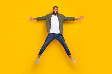 Fototapeta na wymiar Full length photo of cute cheerful man wear khaki shirt jumping high like star isolated yellow color background