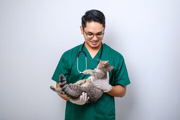 Smiling asian vet wearing green scrubs and stethoscope  holding cat