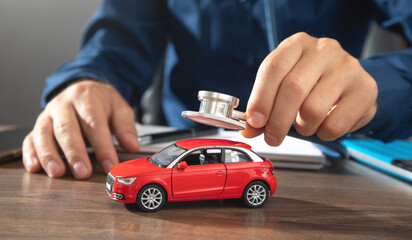 Male hand showing stethoscope over car model.