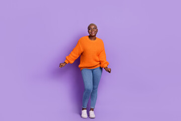 Full body photo of pretty dancing young lady body positive dressed trendy fall orange knitted pullover isolated on purple color background