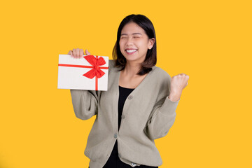 Happy Asian beautiful woman isolated on bright yellow background. She was excited about the voucher...