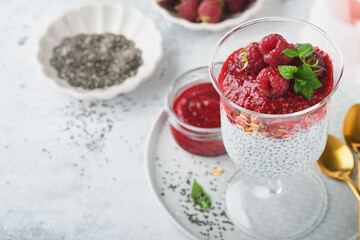 Chia pudding. Healthy vanilla chia pudding in glass with fresh raspberries and mint on white background. Vegan healthy breakfast.