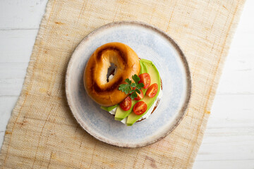 Toasted baggel with cream cheese, avocado and organic cherry tomatoes. Vegan brunch.