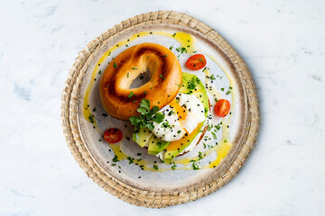 Toasted baggel with cream cheese, avocado, organic cherry tomatoes and poached egg. Vegan brunch.