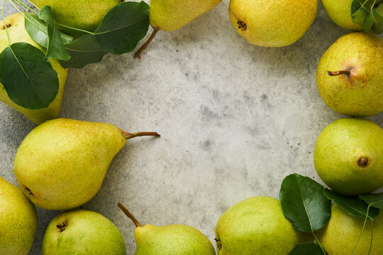 Pears. Fresh sweet organic pears with leaves in wooden box or basket on old stone tile background. Frame of autumn harvest fruits. Top view. Food background. Mock up.