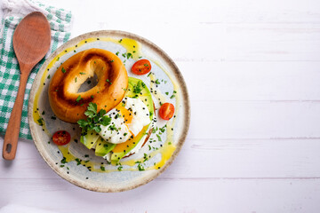 Toasted baggel with cream cheese, avocado, organic cherry tomatoes and poached egg. Vegan brunch.