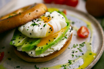 Toasted baggel with cream cheese, avocado, organic cherry tomatoes and poached egg. Vegan brunch.