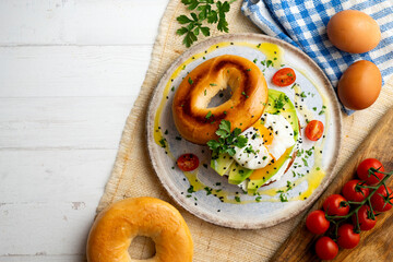 Toasted baggel with cream cheese, avocado, organic cherry tomatoes and poached egg. Vegan brunch.
