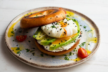 Toasted baggel with cream cheese, avocado, organic cherry tomatoes and poached egg. Vegan brunch.