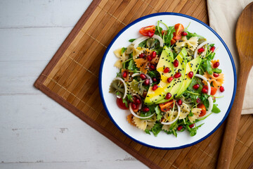 Argula salad with pasta bows, avocado, cherry tomatoes, pomegranate and sesame.