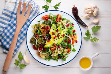Argula salad with pasta bows, avocado, cherry tomatoes, pomegranate and sesame.