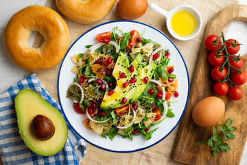Argula salad with pasta bows, avocado, cherry tomatoes, pomegranate and sesame.
