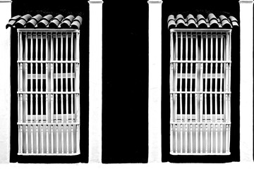 Typical colonial facade with large white and black windows, and Spanish roof.