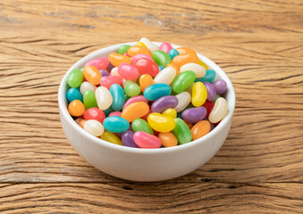 Colorful jelly beans in a bowl over wooden table