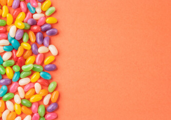 Frame of colorful jelly beans over orange background with copy space