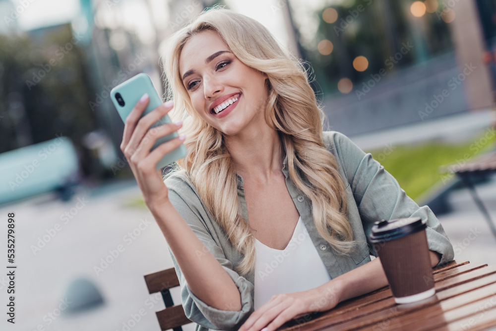 Sticker Portrait of attractive cheerful wavy haired girl using gadget chatting spending spare time day weekend drinking coffee outside