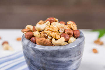 Fototapeta na wymiar Marble bowl filled with shelled almonds, walnuts, cashew nuts