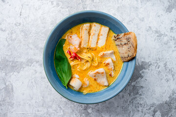 Malaysian noodles laksa soup with chicken, prawn and tofu in a bowl on grey background