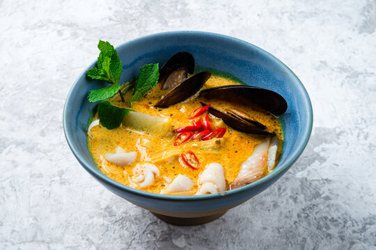 Malaysian noodles laksa soup with chicken, prawn and tofu in a bowl on grey background