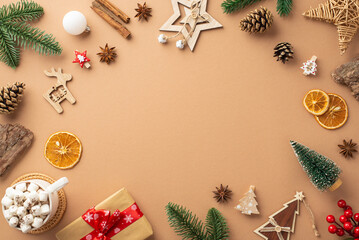 Fototapeta na wymiar Top view photo of christmas decorations wood ornaments giftbox cup of cocoa mistletoe pine cones branches bark cinnamon dried orange slices on isolated beige background with copyspace in the middle