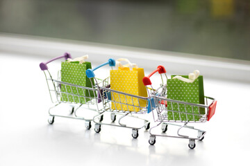 Miniature shopping cart on wooden mock up over blurred green garden on day noon light, Image for Shopping online concept.