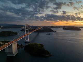 Obraz premium Light traffic on long suspension bridge under sunset afterglow as night falls