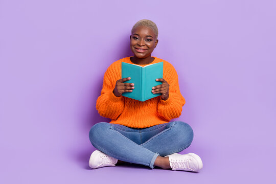 Full body photo of cheerful charming lady sitting floor hold book isolated on violet color background