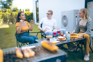 Happy family cheering with barbecue dinner outdoor - Group of people having fun at weekend meal - BBQ Food, taste and summer concept, Man cooking meat on barbecue grill at summer party