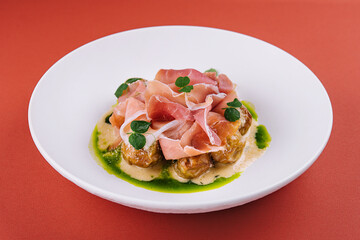 Salad with prosciutto and artichokes on a white plate