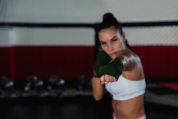 Young woman or girl mixed martial arts boxer fighter training in the octagon cage. Female bare...