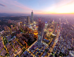 Obraz premium Aerial view of Downtown Taipei at dusk, the vibrant capital city of Taiwan, with 101 Tower standing among modern skyscrapers in Xinyi District and city lights dazzling under dramatic twilight sky