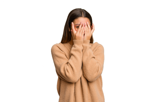 Young Indian woman isolated cutout removal background blink at the camera through fingers, embarrassed covering face.