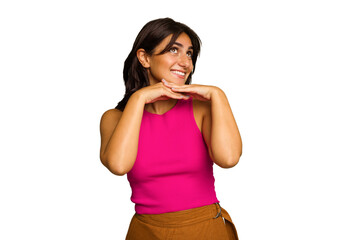 Young Indian woman isolated on green chroma background keeps hands under chin, is looking happily aside.