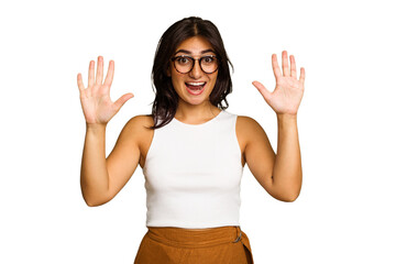 Young Indian woman isolated on green chroma background receiving a pleasant surprise, excited and...