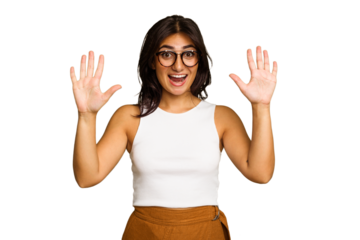 Young Indian woman isolated on green chroma background receiving a pleasant surprise, excited and raising hands.