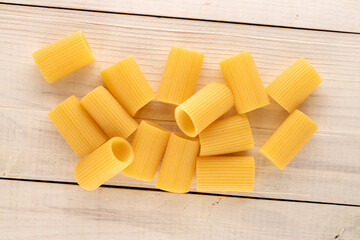 Several raw yellow cannelloni  on a wooden table, macro, top view.