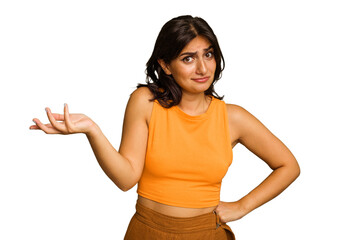Young Indian woman isolated on green chroma background doubting and shrugging shoulders in...