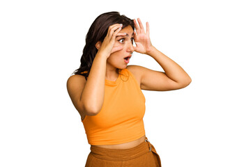 Young Indian woman isolated on green chroma background keeping eyes opened to find a success...