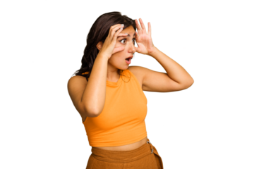 Young Indian woman isolated on green chroma background keeping eyes opened to find a success opportunity.