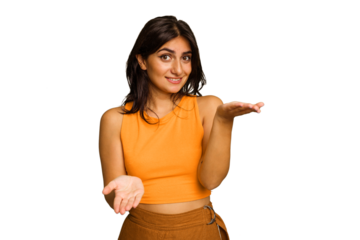 Young Indian woman isolated on green chroma background makes scale with arms, feels happy and confident.
