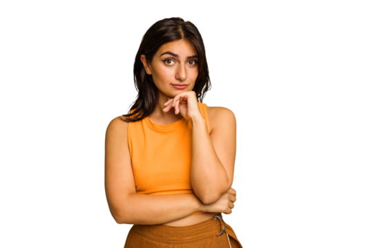 Young Indian woman isolated on green chroma background suspicious, uncertain, examining you.