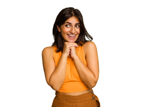 Young Indian woman isolated on green chroma background keeps hands under chin, is looking happily aside.