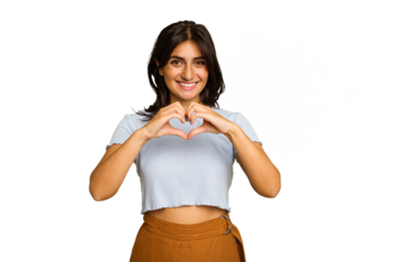 Young Indian woman isolated on green chroma background smiling and showing a heart shape with hands.