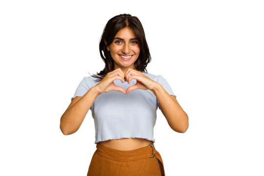 Young Indian woman isolated on green chroma background smiling and showing a heart shape with hands.
