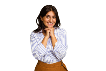 Young Indian woman isolated on green chroma background keeps hands under chin, is looking happily aside.
